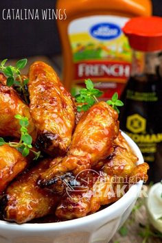 a white bowl filled with chicken wings next to condiments