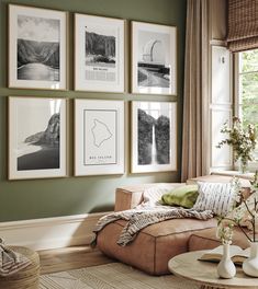 a living room with green walls and pictures on the wall above the couch, along with vases filled with flowers