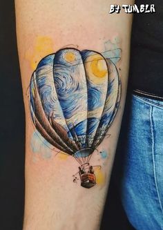 a person with a tattoo on their arm that has an image of a hot air balloon flying