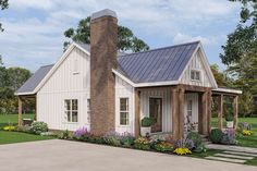 a small white house with a porch and flower garden on the front lawn, surrounded by greenery