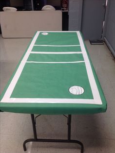 a green table with white lines on it in the middle of a room filled with chairs