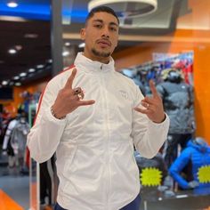 a man standing in front of a display wearing a white jacket and holding his hands up