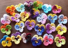 many crocheted flowers are arranged on a brown table top, with one flower in the center