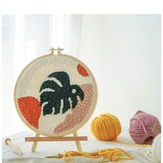 a close up of an embroidery on a wooden stand with balls of yarn in the background