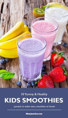 two glasses of smoothie next to bananas, strawberries and blueberries on a wooden table