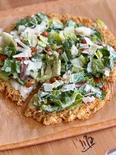 a pizza sitting on top of a cutting board covered in lettuce and other toppings