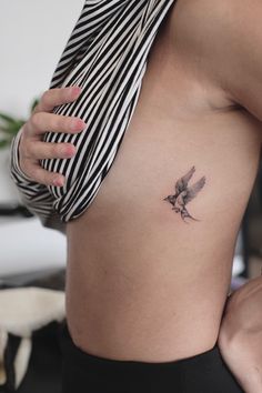 a small bird tattoo on the side of a woman's stomach is shown in this image