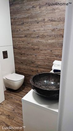 a bathroom with wooden walls and flooring next to a white toilet in the corner