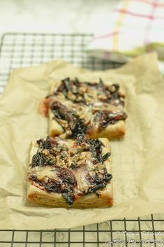 two pieces of pizza sitting on top of a piece of wax paper