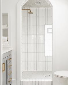 a bathroom with white tile and gold accents