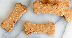 three dog treats on a marble surface with one bone and the other is made out of oatmeal