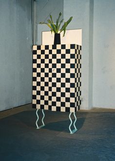 a black and white checkered box with a plant in it's top shelf