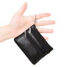 a hand holding a black purse with two zippers