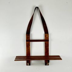 a wooden bench hanging on the wall with a leather strap around it's neck