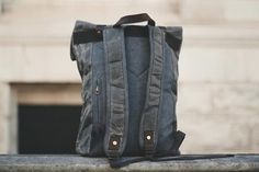 a gray backpack sitting on top of a cement wall