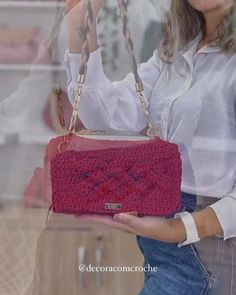 a woman holding a red purse in front of a glass window with her hand on the handle