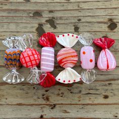 many different colored glass items on a wooden surface with white and red dots around them