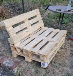 a bench made out of wooden pallets sitting on the ground next to a table