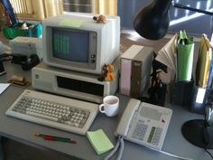 an old computer sitting on top of a desk next to a cup and pen holder