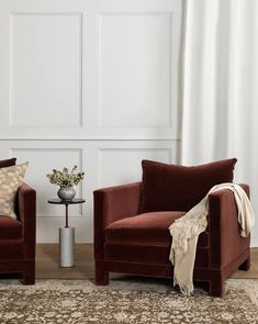 two red chairs sitting next to each other on top of a rug in front of a white wall