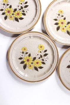 four plates with yellow flowers painted on them