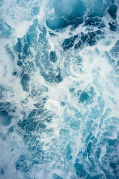 an aerial view of the ocean with blue and white waves crashing in to it's surface