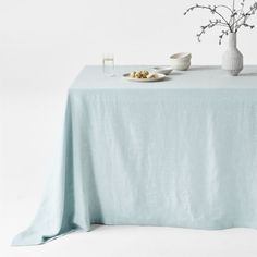 a table topped with a plate of food next to a white vase filled with flowers