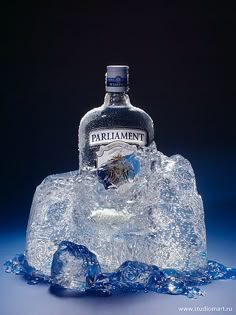 a bottle of parliament vodka sitting on top of an ice block with water splashing around it