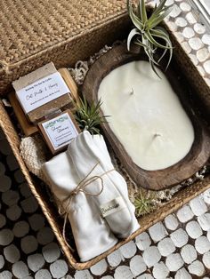 a wicker basket filled with candles and soap next to a small air plant on top of a table