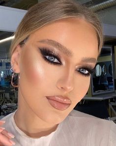 a woman with blue eyes and makeup looks at the camera while posing for a photo