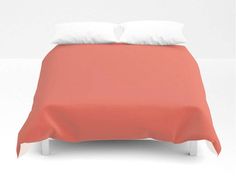 a bed with two pillows on top of it next to a white wall and floor