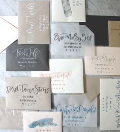 many different types of business cards are laid out on a marble counter top with envelopes and calligraphy