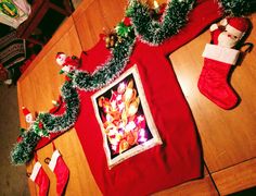 christmas stockings and stocking are on the floor next to a framed photograph with lights in them