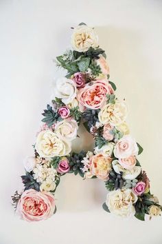 the letter is made up of flowers and greenery on it's sides,