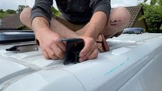 a man sitting on top of a white car with his hands resting on the hood