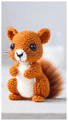 a small crocheted squirrel sitting on top of a white table next to a gray wall