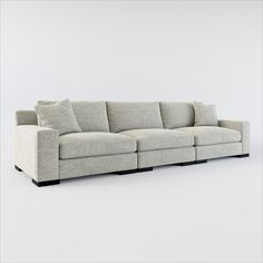 a white couch with pillows on it in front of a gray wall and grey floor