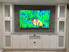 a flat screen tv mounted to the side of a wall in a room with white cabinets