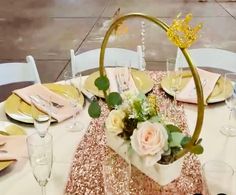 the table is set with gold and white plates, silverware, and flowers in vases