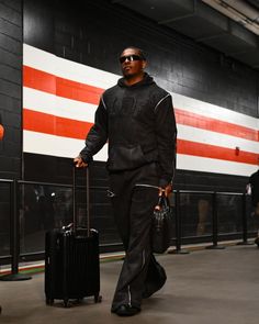 a man walking with two suitcases and an american flag painted on the wall behind him