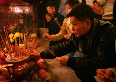 a group of people standing around a bowl filled with sticks and candles on top of a table