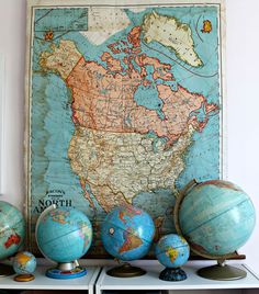 several globes are sitting on a shelf in front of a map