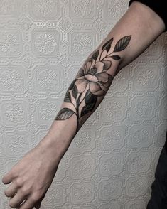 a person with a flower tattoo on their arm and the other hand is holding something