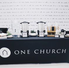 there is a one church sign on the table with coffee cups and blenders in front of it