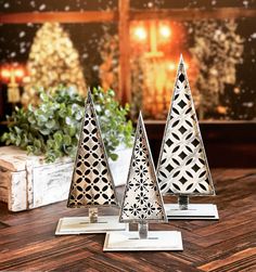 three metal christmas trees sitting on top of a wooden table