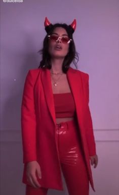 a woman with horns on her head wearing red leather pants and a red blazer