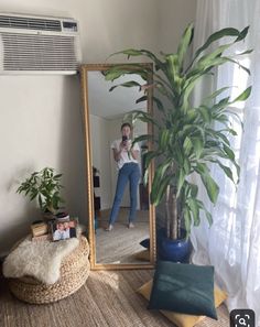 a woman taking a selfie in front of a mirror next to a potted plant