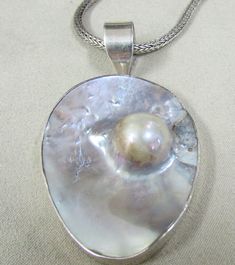 "Sterling silver blister pearl necklace. The pendant is 2\" tall x 1 9/16\" wide. The ring on top and bail add 13/16\" to the height. The pictured 20\" woven 925 chain is included. Good condition. NK-9" Artisan Sterling Silver Pearl Pendant Jewelry, Artisan Sterling Silver Jewelry With Pearl Pendant, Artisan Silver Jewelry With Pearl Drop, Sterling Silver Pendant Necklace With High Luster, Silver Oval Necklace With Pearl Drop, Silver Oval Pearl Drop Necklace, High Luster Sterling Silver Pendant Necklace, Unique Silver Necklace With Pearl Drop, Unique Silver Pearl Drop Necklace