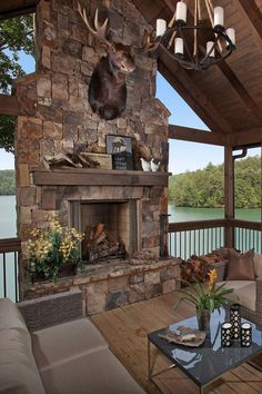 a living room with a stone fireplace and deer head mounted to the wall above it