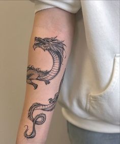 a woman's arm with a tattoo on it that has a dragon in the middle